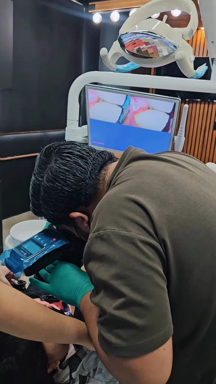 Odontólogo atendiendo a un paciente en el sillón dental mientras revisa una pantalla con imágenes intraorales