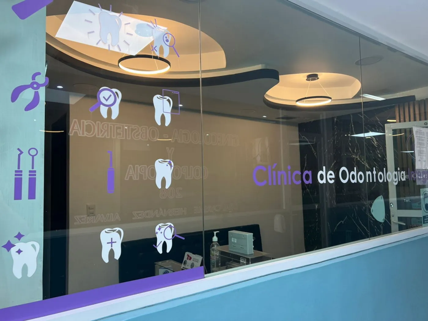 Fachada de cristal con el nombre de la clínica y gráficos de dientes en violeta