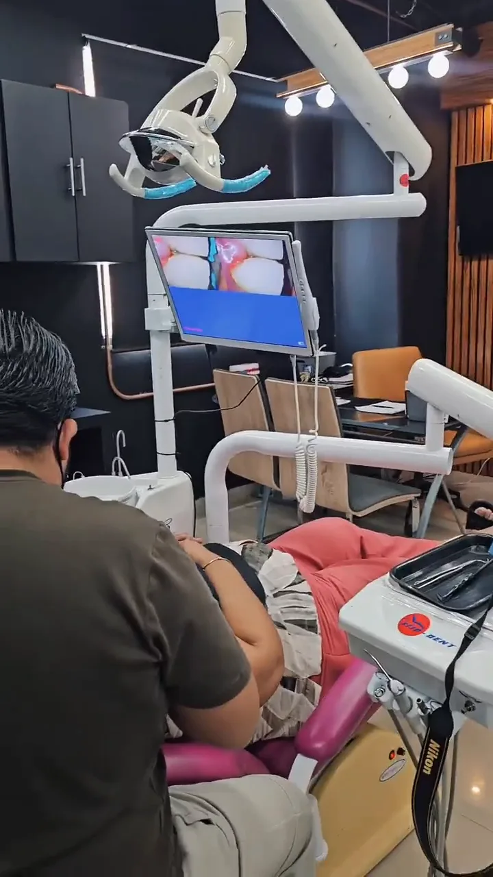 Consultorio de la clínica con un odontólogo atendiendo a un paciente en el sillón dental
